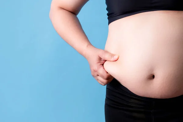 太りすぎの女性は青い背景に彼女の腹に脂肪をキャッチします 隔離された背景 — ストック写真