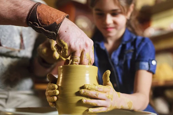 the master with the child molds a clay jug.