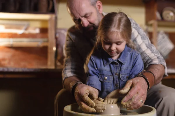 the master with the child molds a clay jug.