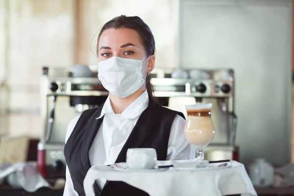 work of a waiter in a restaurant in a medical mask