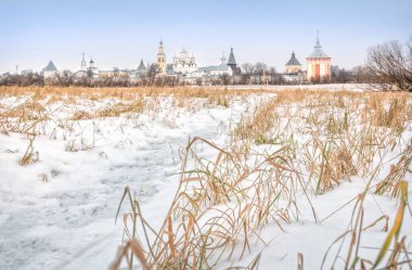 Vologda 'daki Spaso-Prilutsky manastırı bulutlu bir günde karlı bir tarlada kuru otlar eşliğinde görünüyor.