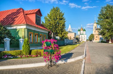 Sokakta eski ahşap bir ev ve güneşli bir yaz akşamında Kolomna Kremlin tapınakları. Başlık: Lazhechnikova Caddesi