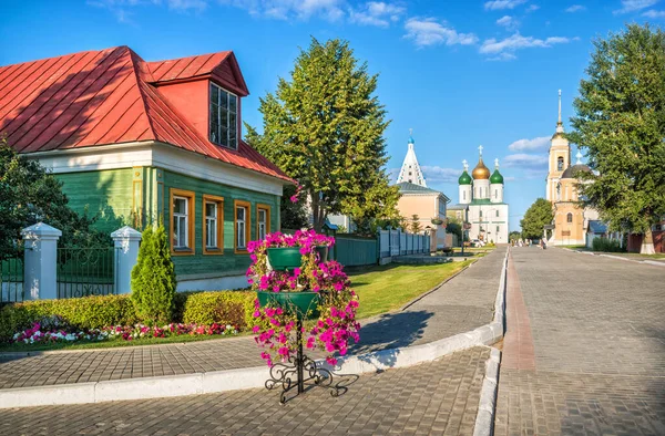 Wooden old house on the street and temples of the Kolomna Kremlin on a summer sunny evening. Caption: Lazhechnikova street