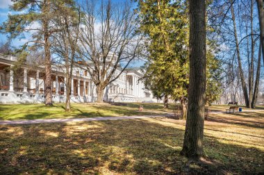 Ostafyevo 'daki Main House' un kar beyazı binası güneşli bir bahar gününde park ağaçlarının arasında.