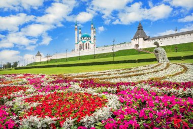 Kazan Kremlin 'deki Kul Şerif Camii ve mavi gökyüzünün altında beyaz bulutlu renkli bir tavus kuşu şeklinde çiçekler.