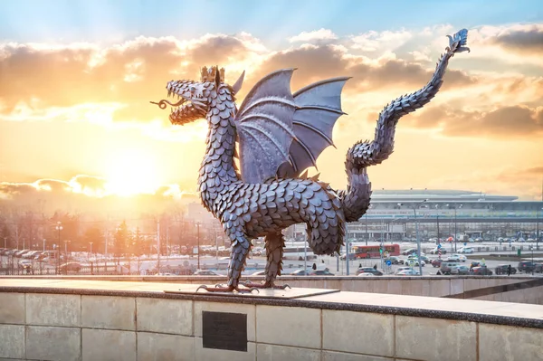 The metal sculpture of the Dragon Zilant in Kazan on the background of the sunset ginger sky and the sun