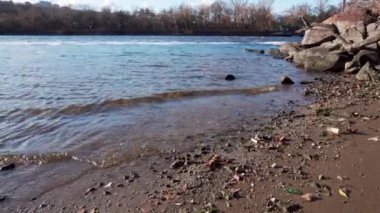 Küçük dalgalı mavi nehir, kayalık sahil. Okyanus ya da deniz, yüzeyinde köpük olan koyu mavi renktedir. Soğuk su.