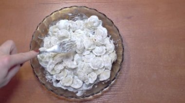 Elinde çatal olan kadın ravioli ile tabağı karıştırıyor.