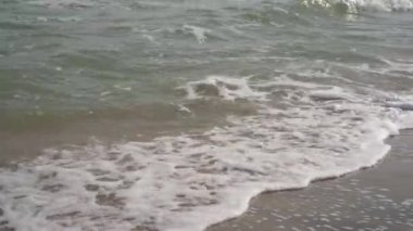Kumlu sahilde küçük dalgalar. Sahilde beyaz köpük