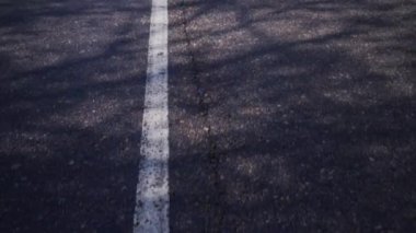 Asfalt yolda beyaz ayrım çizgisi. Otoyol yemyeşil bitki örtüsünden geçer. Bir ülke arabayla veya bisikletle yürür.
