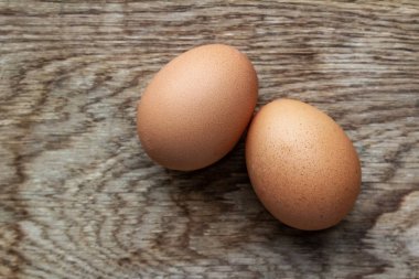 Tahta arka planda iki kahverengi yumurtayı kapat, protein kaynağı, düz uzan.