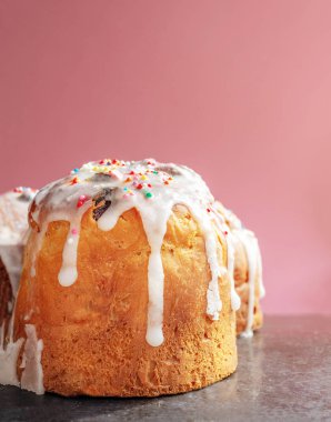 Beyaz kremalı Paskalya pastası ve güneşte pembe bir arka planda izole edilmiş renkli konfeti, sünger pastası. Kek pişirmenin gözenekli yapısı. Sabah yemeği.