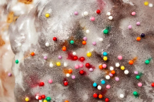 Zuckerfarbenes Konfetti liegt auf einem weißen Zuckerguss-Kuchen, Textur aus Zuckerguss auf einer Cupcake-Oberfläche in Nahaufnahme, rosa, blaue und weiße Bonbons — Stockfoto