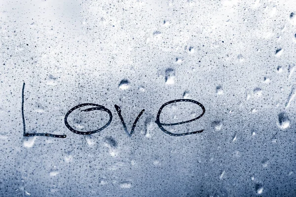 Inscription love on a wet window pane with raindrops — Stock Photo, Image