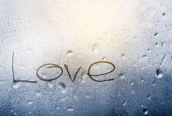 Inscription love on a wet window pane with raindrops — Stock Photo, Image