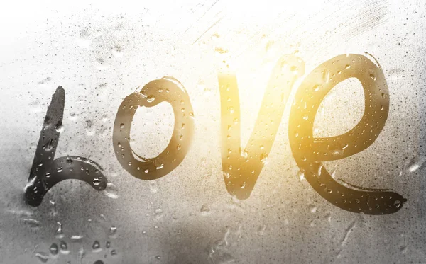 Inscription love with a finger on misted glass in rain — Stock Photo, Image