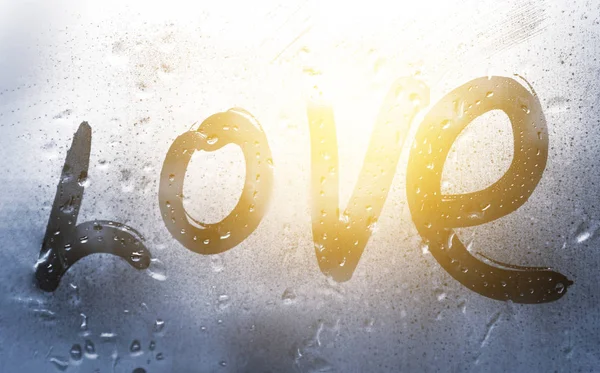 Inscription love with a finger on misted glass in rain — Stock Photo, Image