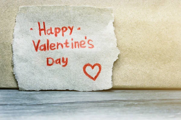 Η επιγραφή Happy Valentine 's Day με κόκκινο μολύβι σε κομμάτι χαρτί craft beige με κόκκινη καρδιά. Αντιγραφή χώρου για κείμενο. — Φωτογραφία Αρχείου