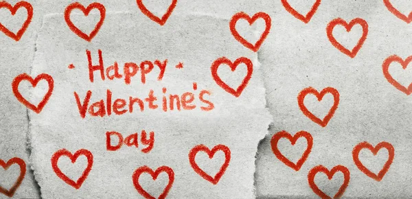 The inscription Happy Valentine's Day in red pencil on piece of craft paper with many painted red hearts — Stock Photo, Image