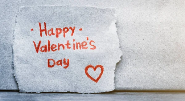 Η επιγραφή Happy Valentine 's Day με κόκκινο μολύβι σε ένα κομμάτι χαρτί με κόκκινη καρδιά. Αντιγραφή χώρου για κείμενο. — Φωτογραφία Αρχείου
