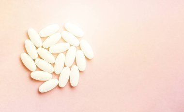 Pembe arka planda güneş ışığıyla izole edilmiş tablet ve haplardan oluşan beyaz daire..