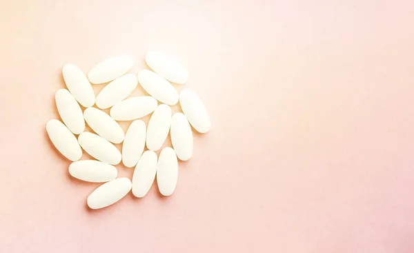 Bílý kruh z tablet a pilulky izolované na růžovém pozadí se slunečním světlem. — Stock fotografie