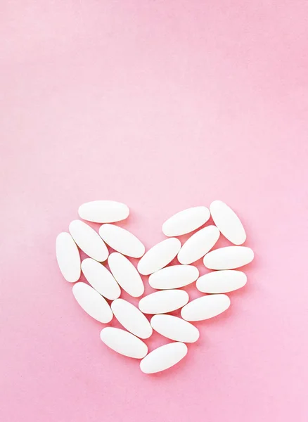 Tvar srdce z pilulek na léčbu, koncept léčby a zdravotní péče na růžové — Stock fotografie