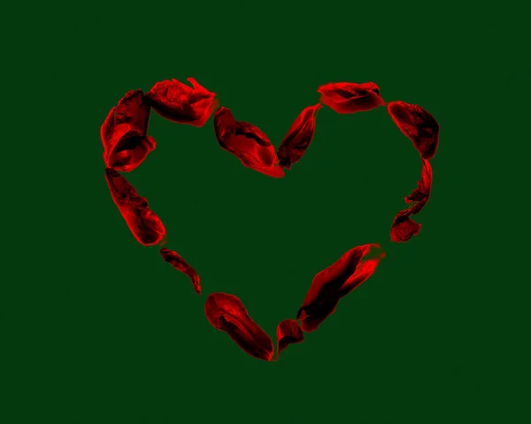 Corazón de los pétalos rojos aislados en verde oscuro — Foto de Stock