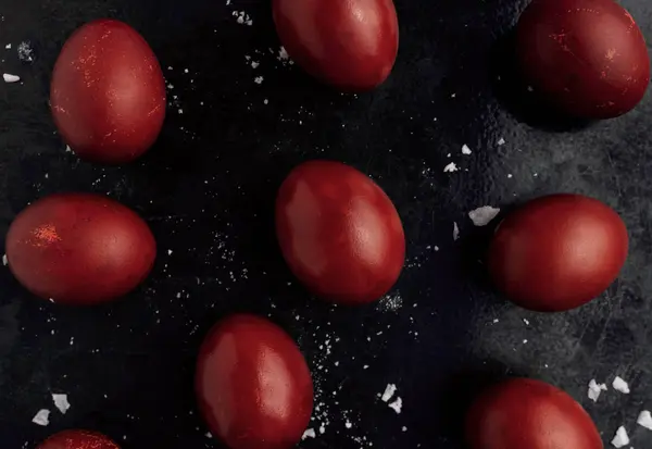 Easter eggs painted in red monochrome style close up on a black surface with icing crumbs. Eggs with stains, scuffs, scratches. handmade painted eggs. Flat lay — 스톡 사진