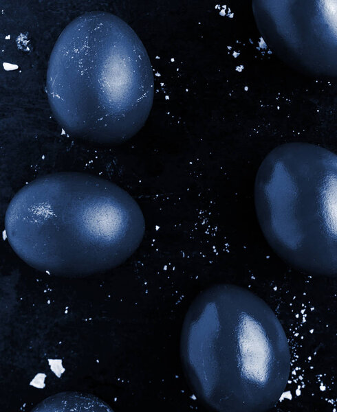 Easter eggs painted in classic blue monochrome style close up on a black surface with icing crumbs. Eggs with stains, scuffs, scratches. handmade painted eggs. Flat lay