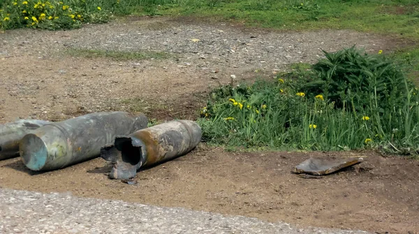 砲弾はアスファルト道路の脇にあり、タンポポが咲き、草は緑に変わります — ストック写真