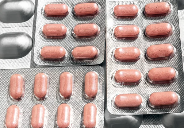 Varias ampollas con comprimidos de color rosa de diferentes formas de primer plano Imagen de archivo