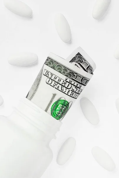 Roll of money Bills in white pill bottle with white pills. The High Cost of Health Care. Pills and US Currency in Pill Bottles — Stock Photo, Image