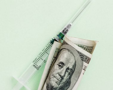 American dollar with Benjamin Franklin and empty syringe on pink background, concept of drugs, spread and dirty money, flat lay