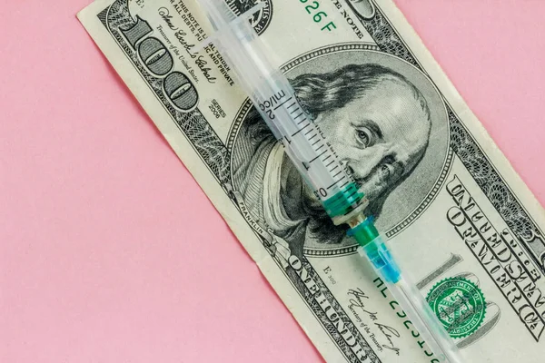 American dollar and empty syringe on pink background, vaccination concept, high cost of medical servicesy, flat lay — Stock Photo, Image