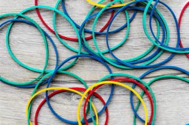 Açık ahşap dokuda renkli lastik bantlar.