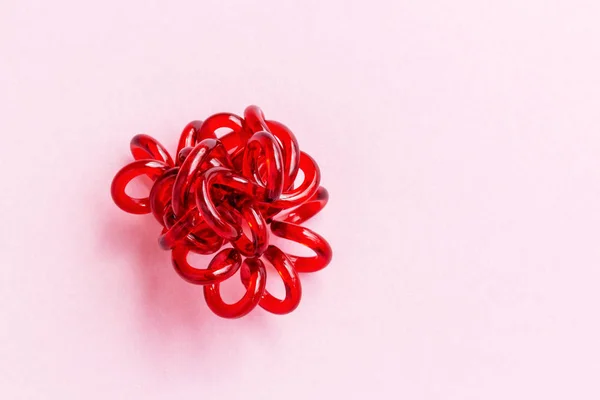 Red spiral rubber band twisted. Elastic hair tie on pink background — 图库照片