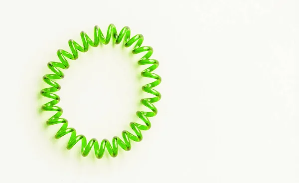 Grünes Spiralgummiband. Elastische Haarbinde auf weißem Hintergrund Nahaufnahme, Kopierraum Stockbild