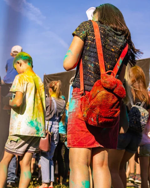 УФА, РОССИЯ - 5 июля 2019 года: девушка в Холи рисует в юбке и с мягким пушистым красным рюкзаком стоит спиной к голубому летнему небу, иностранному празднику в России — стоковое фото