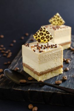 Çağdaş kahve mini kremalı kekler. Siyah arka planda çikolata elementleriyle süslenmiş.