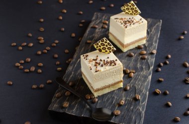 Çağdaş kahve mini kremalı kekler. Siyah arka planda çikolata elementleriyle süslenmiş.