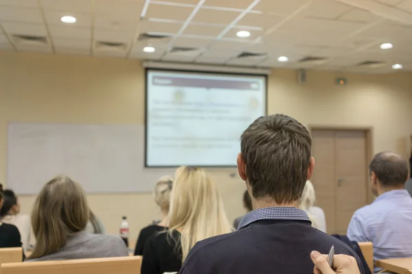 Vista trasera de los estudiantes escuchando atentamente al profesor cerca de la pizarra blanca — Foto de Stock