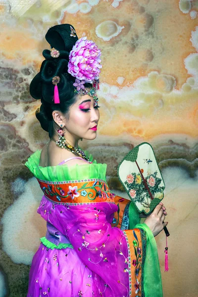 Chinese beautiful girl in traditional Chinese dress with fan in a half-turn — ストック写真