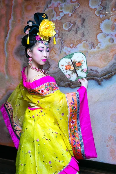 Bela mulher chinesa de pé em meia volta no vestido tradicional nacional chinês amarelo com ventilador — Fotografia de Stock