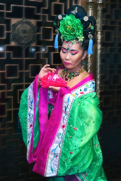 Atractiva joven mujer china en ropa tradicional china sosteniendo flor — Foto de Stock