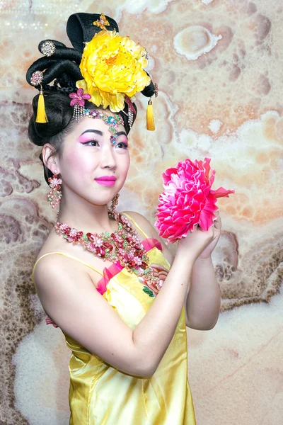 Portret van een mooie Chinees meisje in gele jurk met bloem, in de traditionele Chinese stijl. — Stockfoto