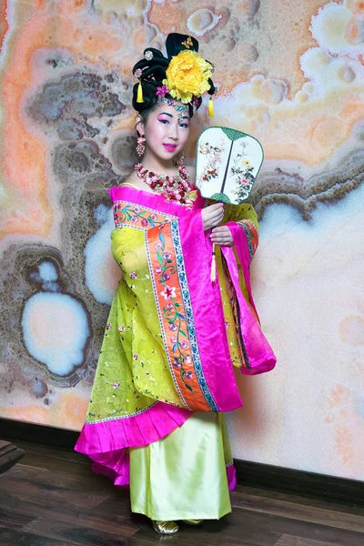 Geisha. Wanita muda dengan kimono kuning dengan kipas angin dan bunga di rambutnya . — Stok Foto