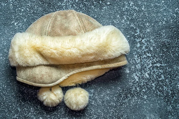 Women's winter hat leather and fur on a dark cement background