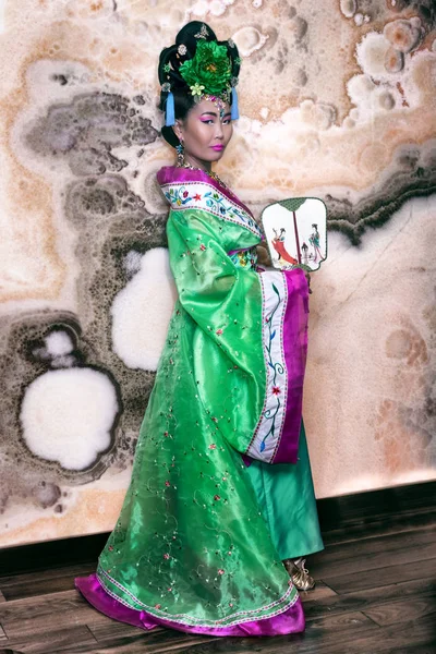 Chica china con un ventilador en un vestido chino tradicional verde — Foto de Stock