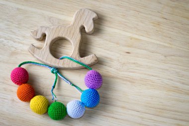 Arkadan kovalayan oturan bebek için örgü boncuk ve tahta at oyuncak yapılmış kolye. Örme boncuk. Askı Hemşirelik kolye.